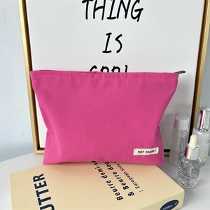 Close-up of pink canvas cosmetic bag with May Rabbit label on a lifestyle desk setup