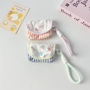 Close-up of floral striped cotton earphone cases with decorative wavy pom-pom lace edges