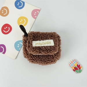 Close-up of brown plush fuzzy AirPods case with mayrabbit label and knit hanging loop