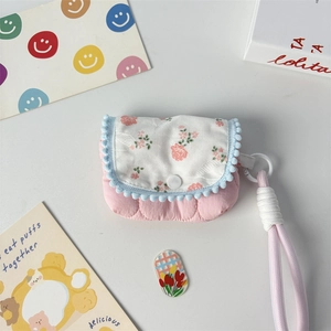 Close-up of small pink floral fabric storage pouch with blue pom-pom lace and carrying rope