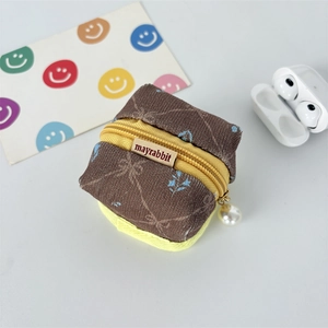 Detail of brown corduroy wireless earphone case with yellow zipper and pearl pendant