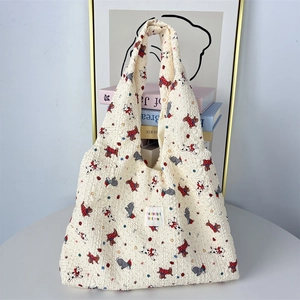 Dettaglio di una borsa tote in tessuto crema con motivo a cane ed etichetta tessuta