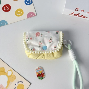 Close-up of yellow floral quilted coin purse with white pom-pom trim and mint lanyard