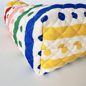 Dettaglio di cuciture trapuntate a rombi e stampa a onde colorate su borsa in tessuto