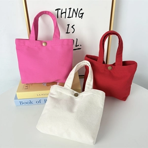 Detail of canvas tote bags in rose, red and white with antique bronze snap button closures