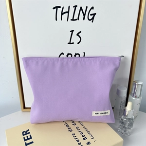 Detailed view of purple canvas makeup bag with durable zipper and brand label