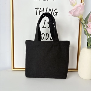 Detail of minimalist black canvas tote bag showing durable fabric texture and sturdy handles