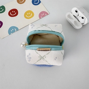 Detail of white corduroy mini storage pouch with pearl zipper and light blue bow patterns