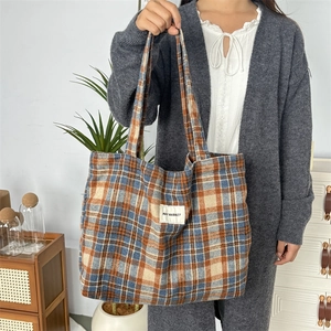 Détail du sac cabas en laine à carreaux avec motifs bleu et orange et étiquette logo