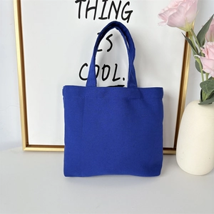 Detail of royal blue canvas tote bag with reinforced handles in a cozy home setting