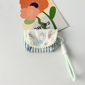 Detailed macro view of floral and striped fabric earphone case with soft pom-pom trim