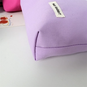Close-up of purple canvas makeup bag showing thick texture and woven logo tag