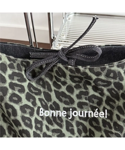 Detail of leopard print tote bag with black drawstring and white embroidered text