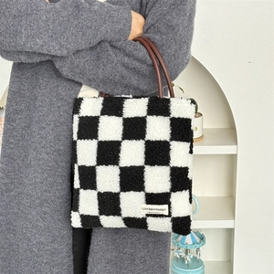 Détail du sac cabas en peluche à damier avec anses en cuir marron et logo de marque
