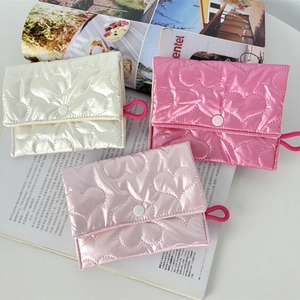 Close-up of heart-quilted flap coin purses in cream, pink and rose colors with snap button
