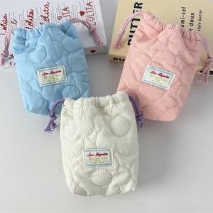 Three heart-quilted drawstring camera bags in pastel blue, pink, and ivory white