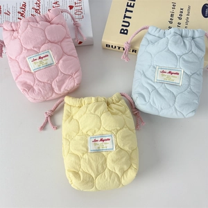 Detailed view of quilted cotton drawstring camera pouches in pastel pink, blue, and yellow