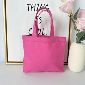 Detailed view of pink canvas tote bag showing stitching and weave texture with rose accent