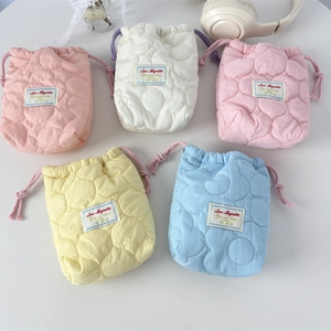 Detailed view of quilted drawstring camera pouches in five pastel colors on a white surface