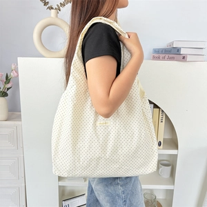 Polka dot canvas tote bag worn by a model in a warm, minimalist home interior setting