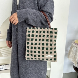 Détail du sac cabas en peluche à damier vert avec poignées marron et étiquette tissée