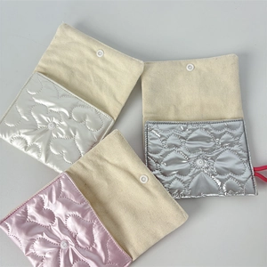 Detail of heart-quilted metallic coin purses in white, silver, and pink with snap buttons