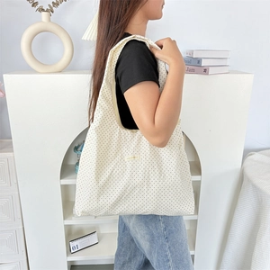 Detail of white polka dot tote bag with stitched fabric label and large capacity design