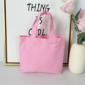 Detailed shot of a pink canvas tote bag with dual handles on a bright white tabletop