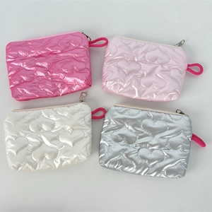 Detail view of four glossy PU leather coin pouches with heart quilting and zipper closure
