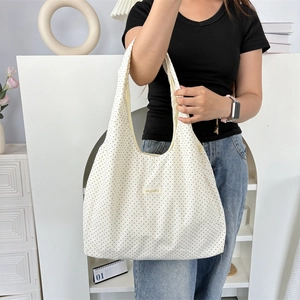 Detailed close-up of a white canvas tote bag featuring black polka dots and logo tag