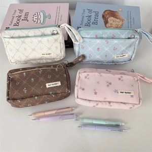 Detail of four colorful corduroy pencil cases with quilted floral pattern and wrist straps