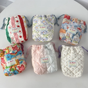Flat lay of six quilted drawstring storage bags with various colorful floral patterns