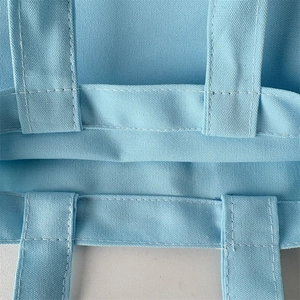 Close-up of light blue canvas tote bag showing double stitching and handle durability
