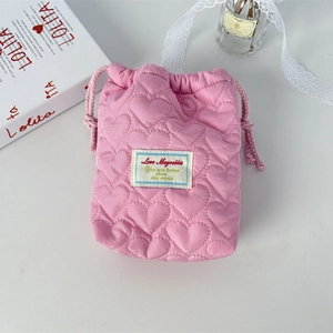 Nahaufnahme der rosa gesteppten Kordelzugtasche mit gepolstertem Stoff auf Tisch