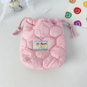 Detailed close-up of pink quilted cotton camera pouch with drawstring and logo tag