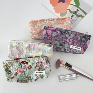 Detailed view of embossed jacquard toiletry bags with floral and butterfly patterns