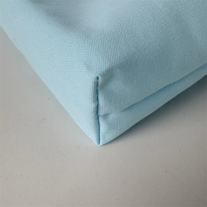 Detailed view of heavy-duty stitching on the bottom corner of a blue canvas tote bag