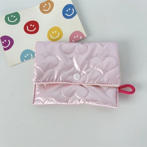 Detail of pink quilted heart coin purse with glossy nylon texture and snap closure