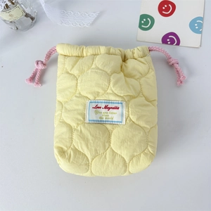 Detailed view of yellow quilted camera pouch with pink drawstring on white background