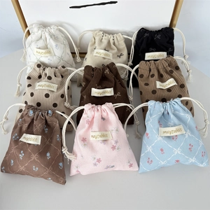 Close-up of assorted corduroy drawstring bags featuring floral and polka dot patterns