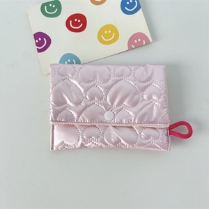 Close-up of quilted heart pattern on glossy pink satin cosmetic bag with white button