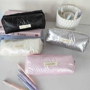 Detailed texture of quilted bow pencil cases in black, silver, white and pink colors