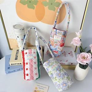 Quilted floral and striped fabric cup sleeves with long straps displayed on books