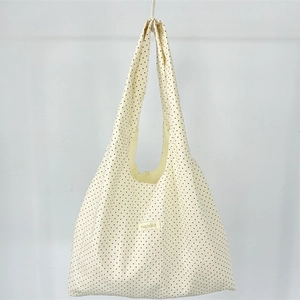Close-up of a woven brand label on a beige canvas tote bag with black polka dots
