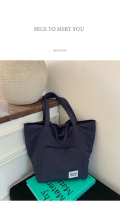 Detail of navy blue nylon tote bag with front pocket and white brand label on books