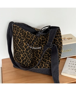 Detailed close-up of leopard print canvas tote bag with black denim strap and French text