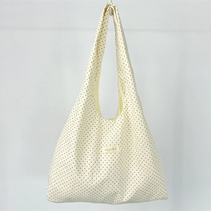 Detailed close-up of mayrabbit brand label on a beige canvas tote bag with black polka dots