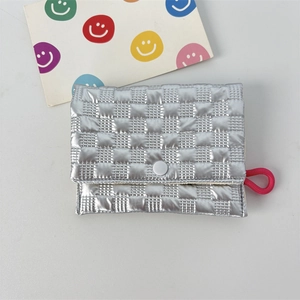 Close-up of silver quilted mini purse with glossy finish, snap button, and pink strap loop