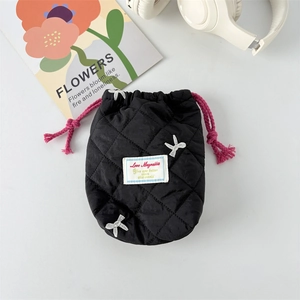 Close-up of black quilted drawstring bag with white embroidered bows and pink ropes