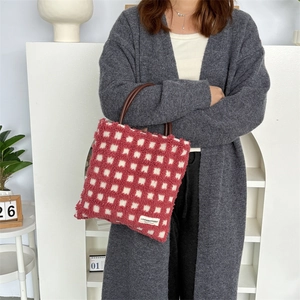Détail du sac cabas en peluche à damier avec anses en cuir et écusson décoratif